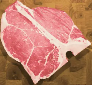 raw porterhouse steak showing both strip and tenderloin. 